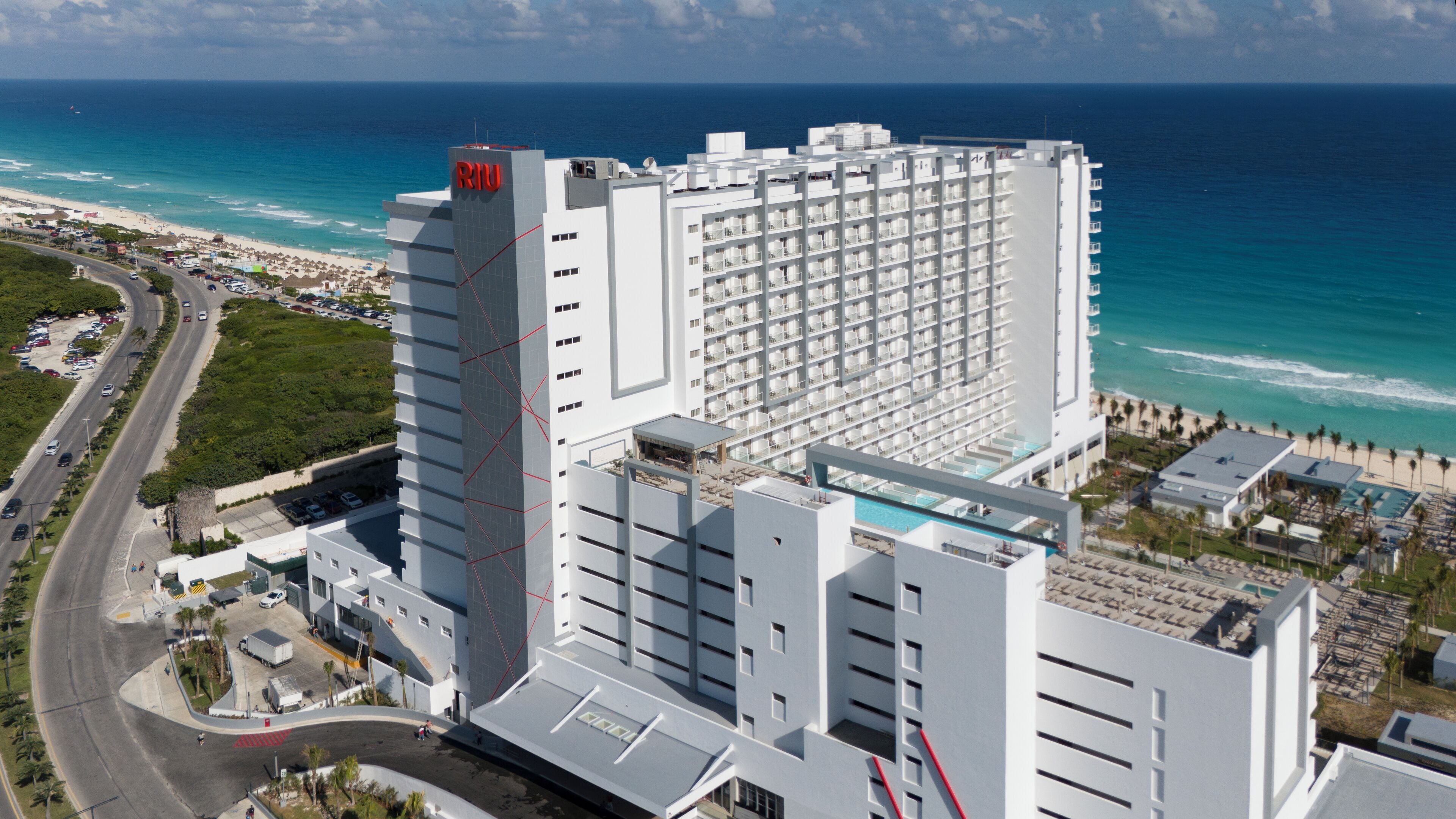 A high-rise hotel with a rooftop pool and a beach view.