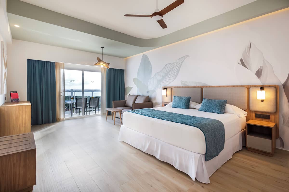 Un dormitorio amplio con una cama grande, mesitas de noche, un ventilador de techo y vistas al exterior.