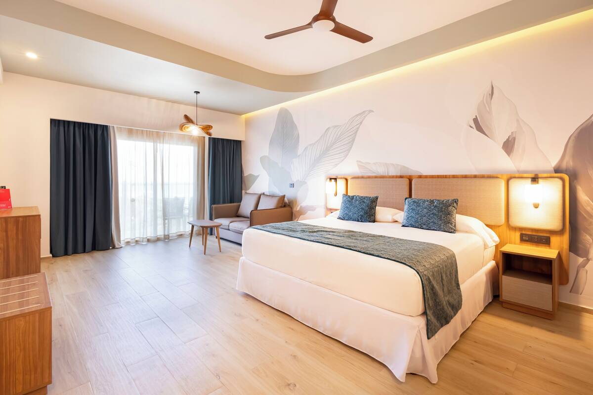 Una habitación de hotel moderna con una cama grande, un escritorio y un sofá.