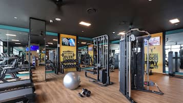 Un gimnasio con cintas de correr, una pelota de ejercicios grande y máquinas de pesas.