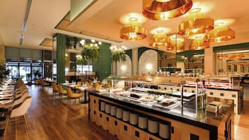 A buffet area with a variety of food options, a central serving station, and a seating area with tables and chairs.