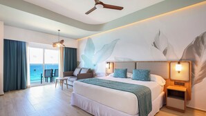 Una habitación de hotel con una cama grande, un escritorio y vista al océano.