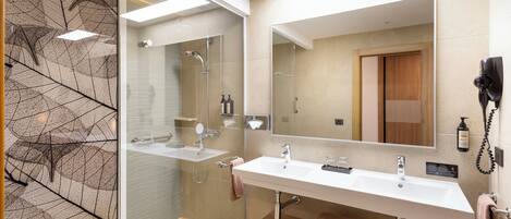 A modern bathroom with a glass shower enclosure, two sinks, and a large mirror.