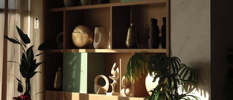 A cozy living room with a wooden bookshelf, two chairs, a table, and a potted plant.