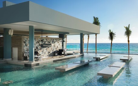 A modern pool area with a bar named "TEQUILA," overlooking the ocean.