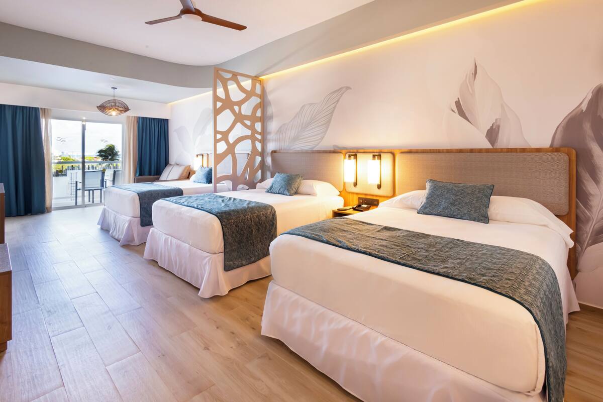 Habitación de hotel con dos camas, balcón y un mural grande en la pared.