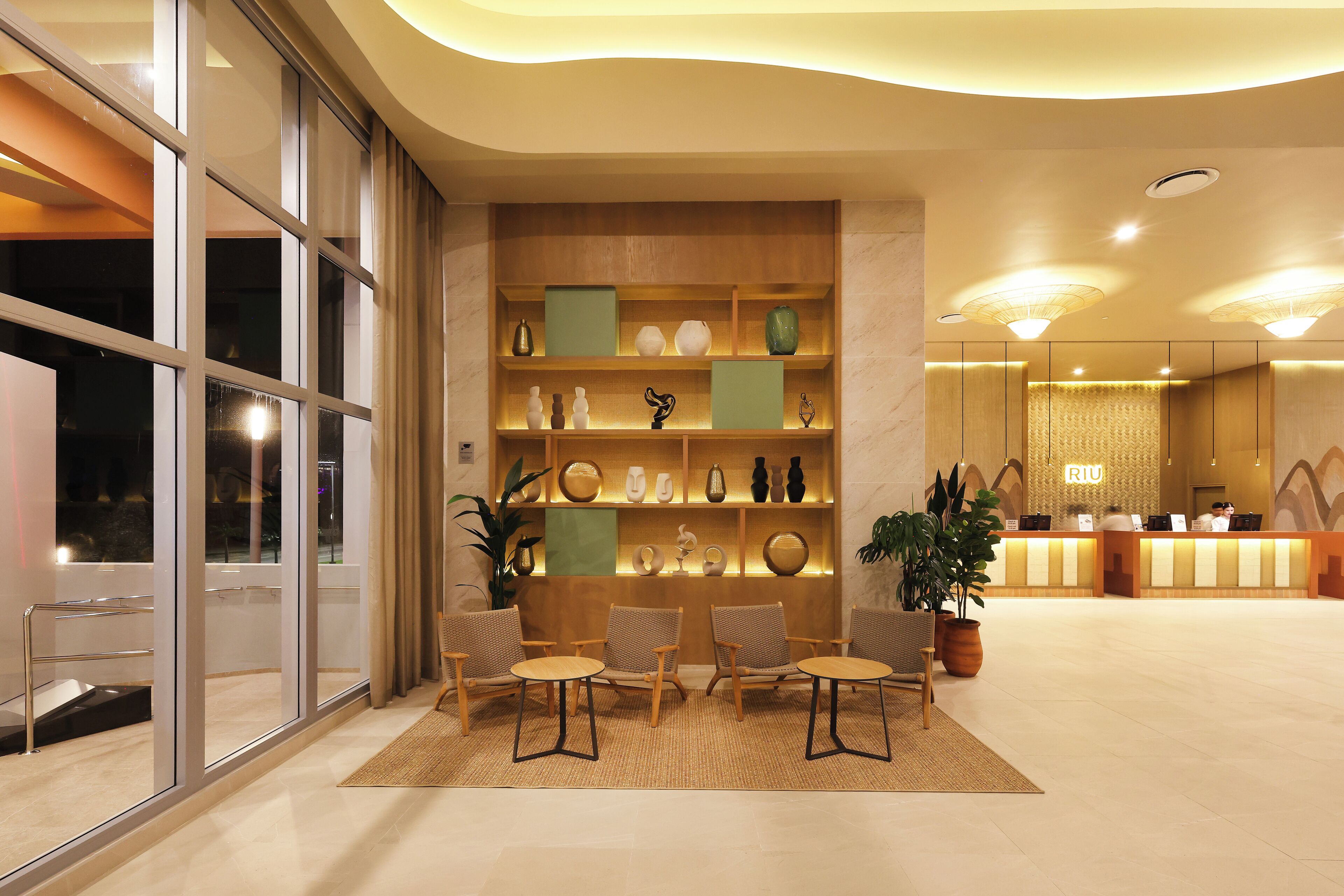 A hotel lobby with a reception desk, seating area, and a display of decorative items.