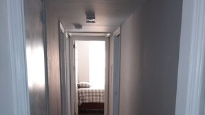 Un pasillo estrecho con suelo de madera y paredes blancas.