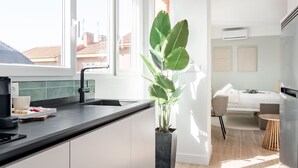 Eine moderne Küche mit einer großen Kochinsel, einem Essbereich mit Tisch und Stühlen sowie einem Blick auf die Stadt durch bodengroße Fenster.