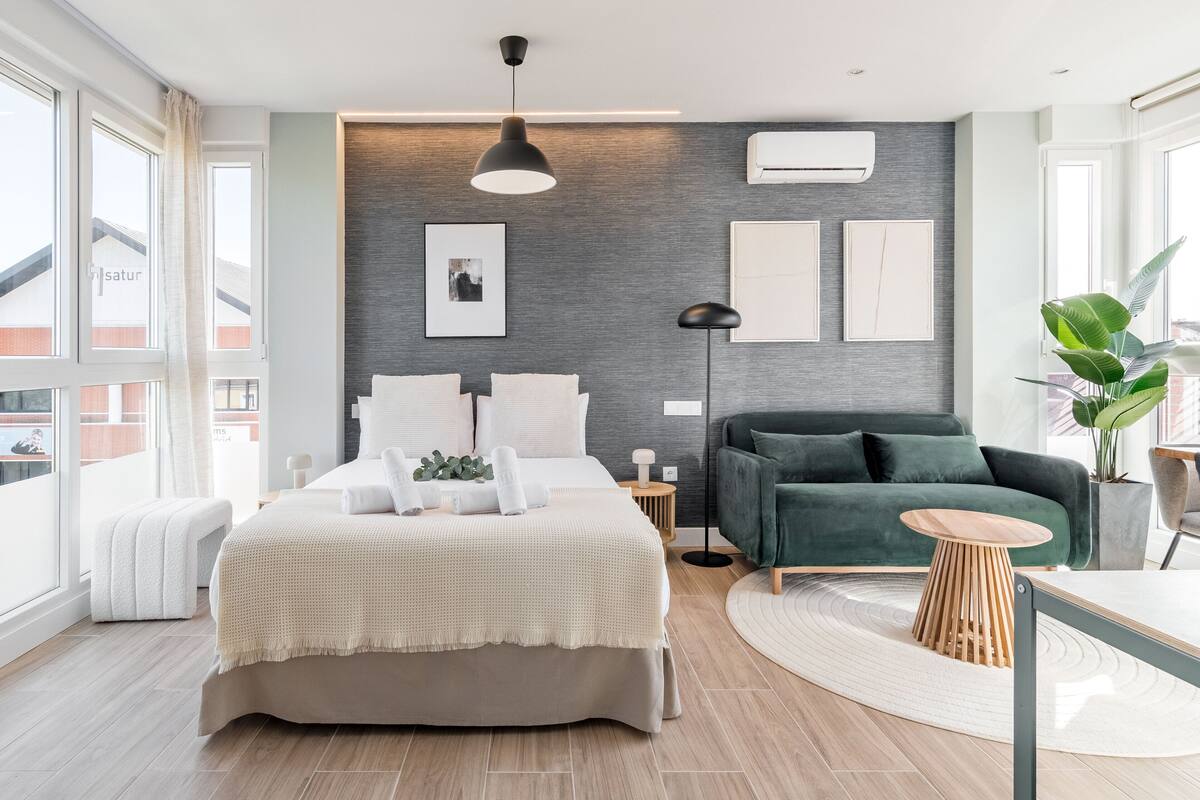Un dormitorio moderno con una cama grande, un sofá verde y una pequeña mesa redonda.