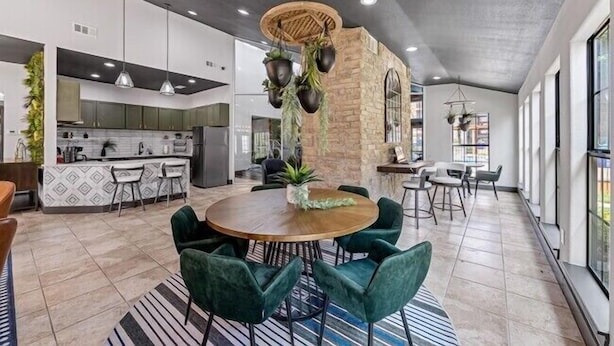 Una cocina amplia con electrodomésticos modernos, un comedor con mesa y sillas redondas, y un gran ventanal que proporciona luz natural.