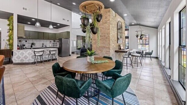 A spacious kitchen with modern appliances, a dining area with round table and chairs, and a large window providing natural light.