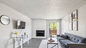 A modern living room with a fireplace, a sofa, a coffee table, and a TV mounted on the wall. - The Landry 278 | Spacious and Cozy 2 Bedroom 1bth (Arlington)