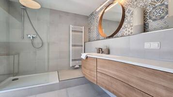 Ein modernes Badezimmer mit einer gläsernen Dusche, einem Holzbadezimmer-Möbelstück und einer Wandfliesen-Verkleidung.