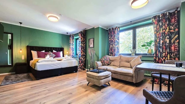 A room with a bed, a sofa, a table, and a chair. - Alpha Apartments: Green Design Studio for 2P (Dortmund)
