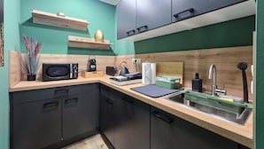 A compact kitchen with dark cabinets, a microwave, a sink, and a wooden countertop. - Alpha Apartments: Green Design Studio for 2P (Dortmund)