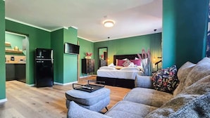 A modern living room with a grey sofa, a dining table, and a kitchen area with a black refrigerator. - Alpha Apartments: Green Design Studio for 2P (Dortmund)
