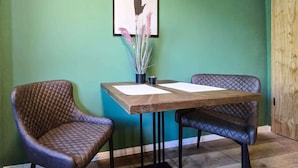A dining area with a wooden table and two cushioned chairs. - Alpha Apartments: Green Design Studio for 2P (Dortmund)