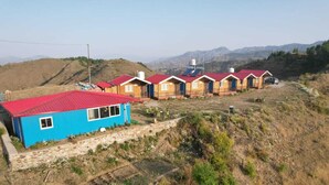 Una fila de cabañas con techos rojos, con montañas al fondo.