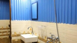 Un baño con lavamanos, espejo, ducha y un cubo de basura.