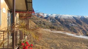 Paisaje montañoso con un edificio de fachada de madera y techo rojo.
