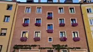 Un edificio de varios pisos con una hilera de ventanas en la planta baja, algunas con macetas de flores.