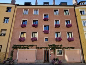 Ein mehrgeschossiges Gebäude mit einer Reihe von Fenstern im Erdgeschoss, einige davon mit Blumenkästen.