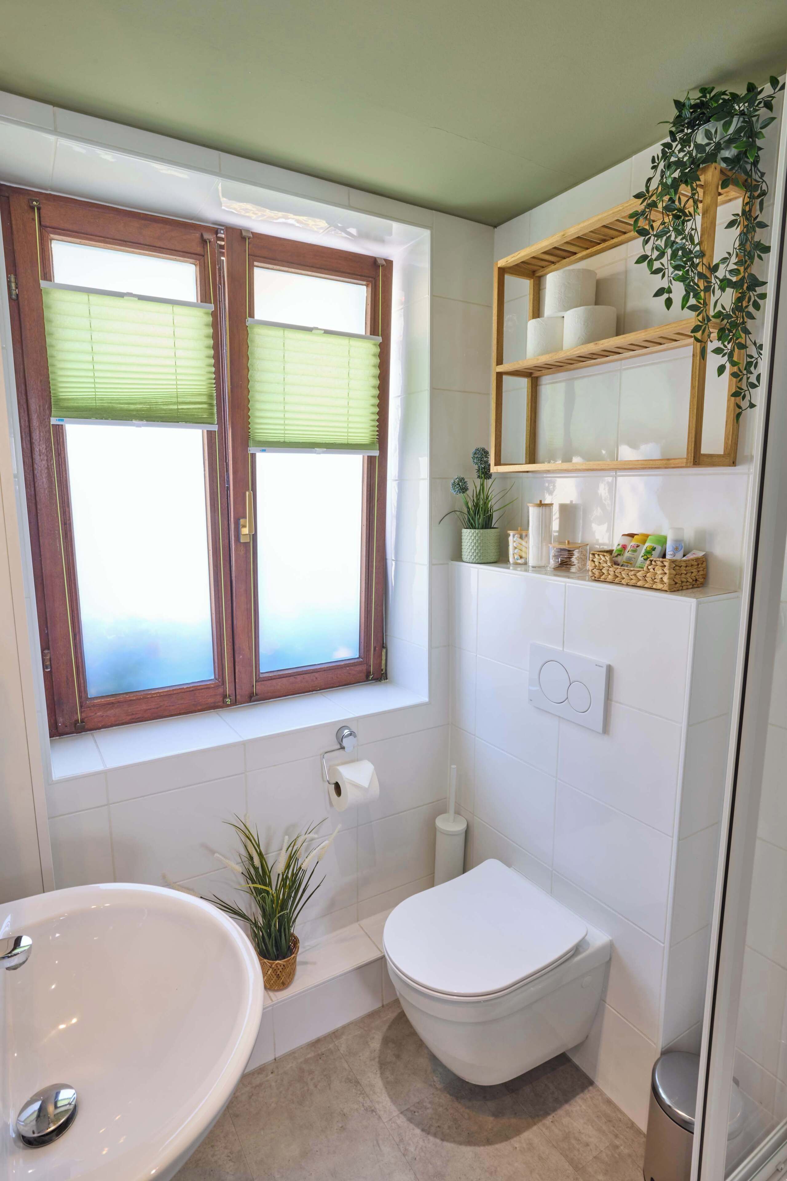 A bathroom with a bathtub, toilet, and window with blinds.