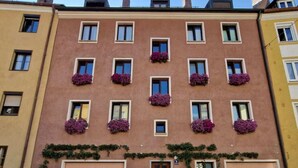 Ein mehrgeschossiges Gebäude mit einer Reihe von Fenstern im Erdgeschoss, einige mit Blumenkästen.