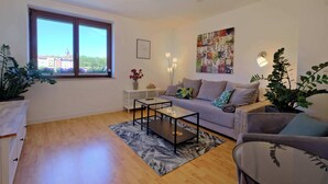Ein Wohnzimmer mit einer Couch, einem Couchtisch und einem großen Fenster mit Blick auf Gebäude.
