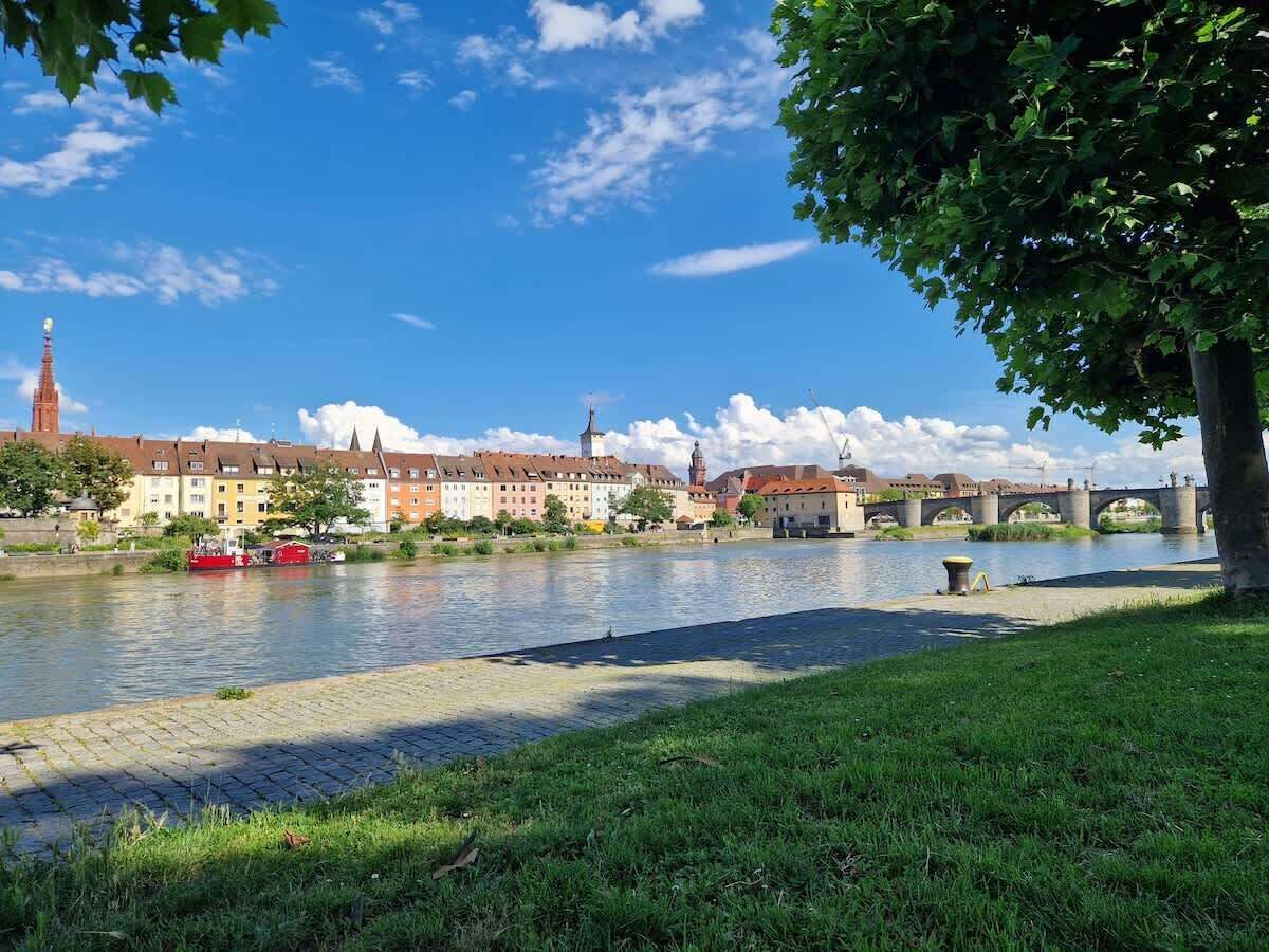 A riverside view with a bridge, buildings, and a red boat.