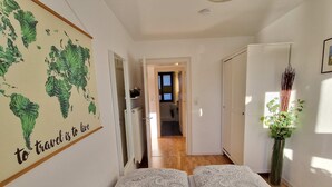 Ein Hotelzimmer mit Bett, einer Weltkarte an der Wand und Blick in die Küche.