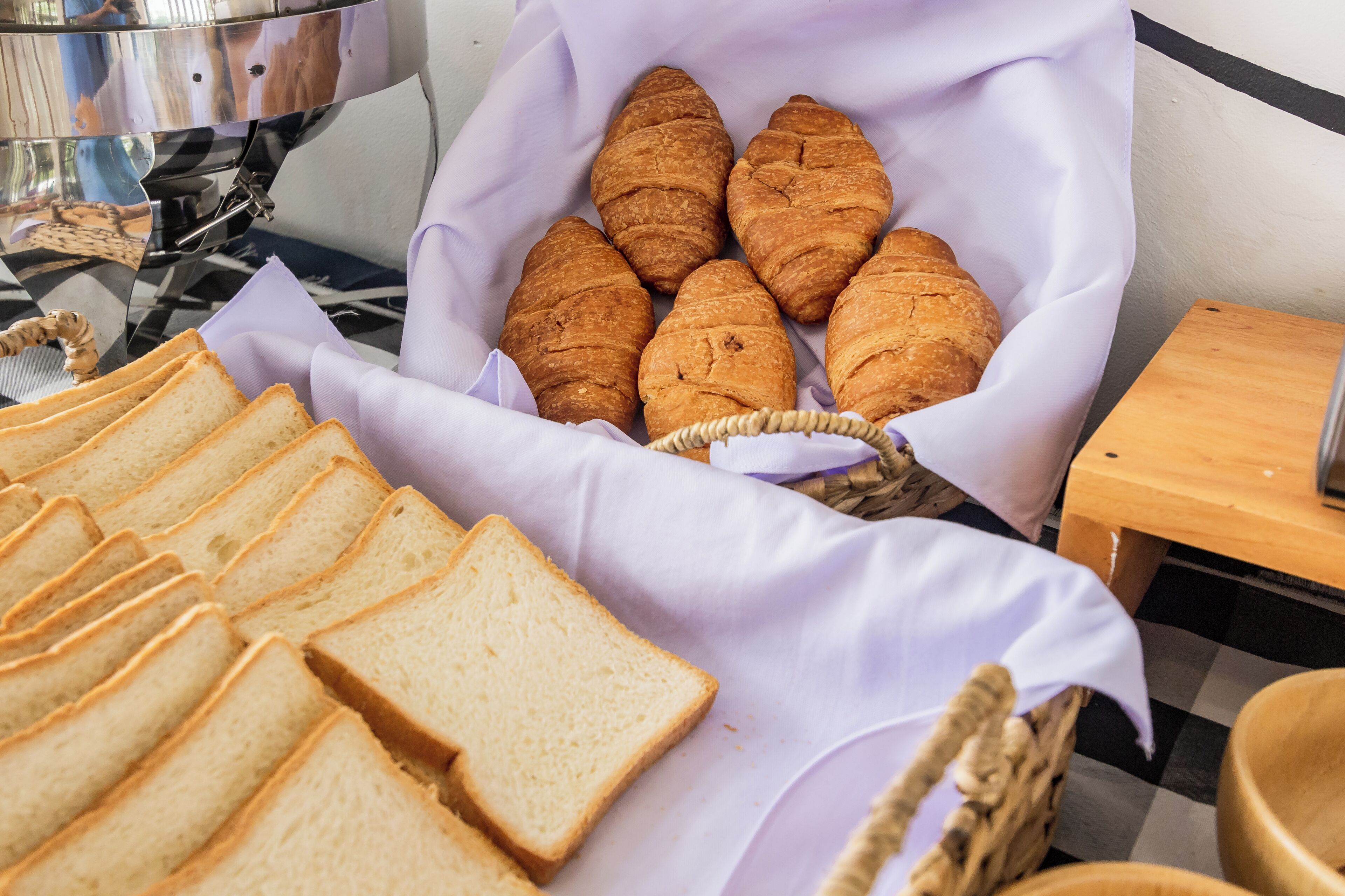 A breakfast buffet with croissants and sliced bread.