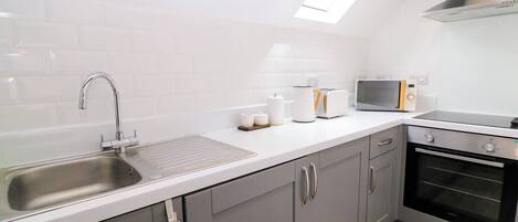A modern kitchen with a stainless steel sink, a toaster, a kettle, and a microwave.