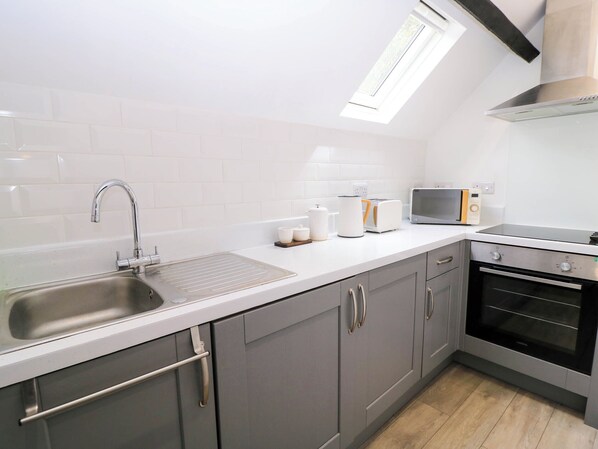 A modern kitchen with a stainless steel sink, a toaster, a kettle, and a microwave.