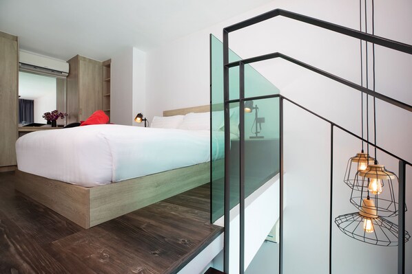 A modern bedroom with a wooden bed, a glass staircase, and pendant lighting.