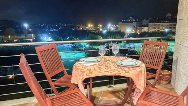 A table set for two with a view of a cityscape at night. - XILGAR Maracaibo Apartment Central next to the Beach (Sanxenxo)