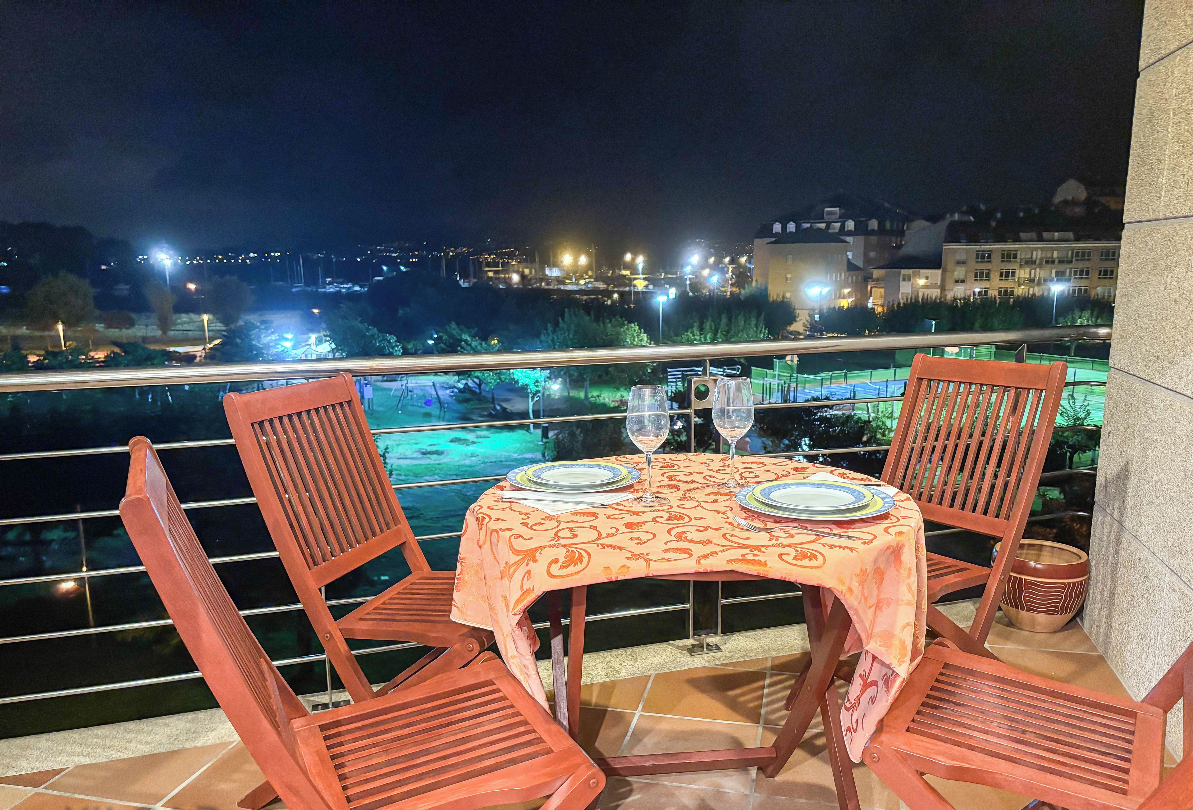 A table set for two with a view of a cityscape at night.