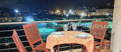 A table set for two with a view of a cityscape at night.
