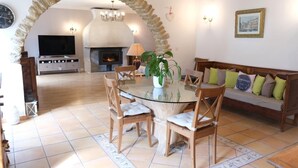 A cozy living room with a stone archway, a fireplace, a glass dining table with chairs, and a sofa with cushions. - Vacation rental house with pool ALTHEN LES PALUDS  LS6-71 (Althen des Paluds)