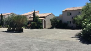 A residential area with two houses, a paved driveway, and surrounding greenery. - LS1-295 MARINADO Mouriès (Mouriès)