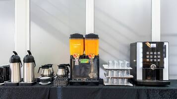 Een koffiehoek met twee espresso machines, een koffiemolen en een koffiekan.