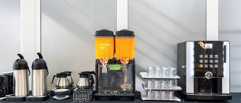 Una estación de café con dos máquinas de espresso, un molinillo de café y una cafetera.
