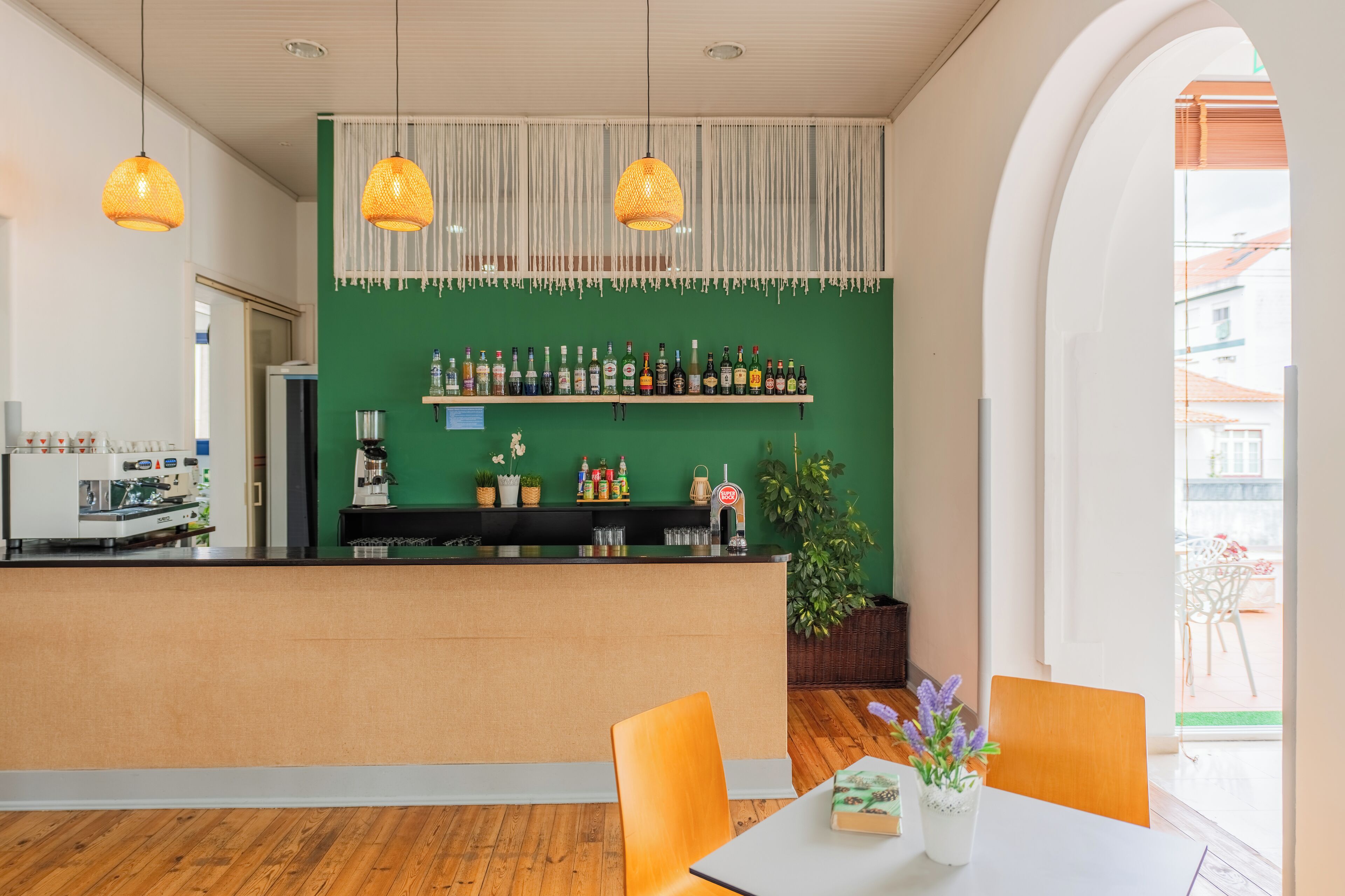 A bar area with shelves of bottles, a coffee machine, and hanging lights.