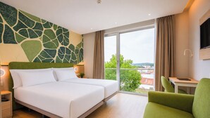 A hotel room with a large bed, a desk, a chair, a TV, and a view of the city. - Spirit Hotel Fonte Real (Monte Real)