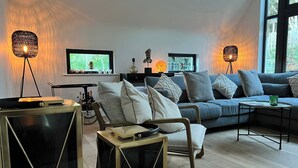 A modern living room with a sofa, a coffee table, and two floor lamps. - Spacious 5-bed House - Garden, Parking & Bbq (Newcastle Upper)