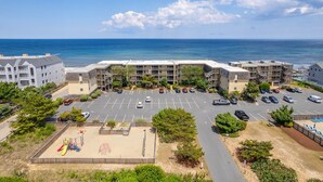 A beachfront hotel with multiple buildings, a parking lot, and a playground area. - GSH2 Ocean-Front Condo, Ocean Views, Comm.Pool (Kill Devil Hills)
