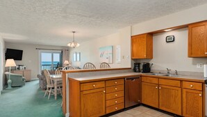 A compact kitchen with wooden cabinets, a built-in dishwasher, and a coffee maker. - GSH2 Ocean-Front Condo, Ocean Views, Comm.Pool (Kill Devil Hills)