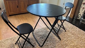 Un coin repas comprenant une table ronde et deux chaises, un meuble en bois et un tapis.
