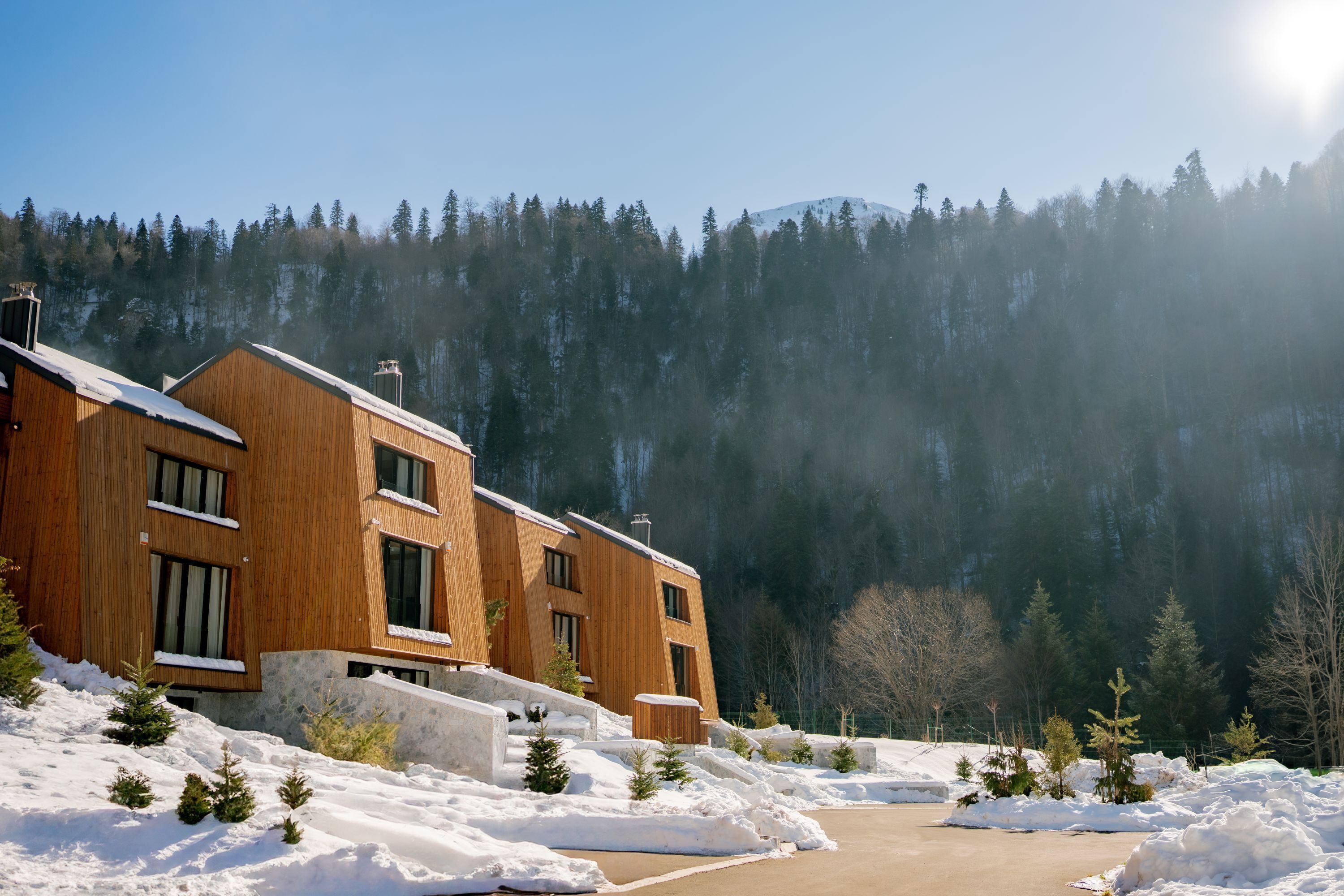 A modern wooden building with multiple windows and a snow-covered landscape.